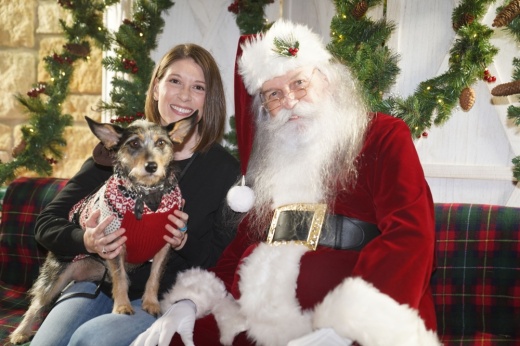 An image of Santa Claus with a pet and their owner.