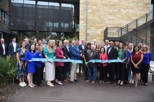 Community members, city council stand behind a ribbon as it is cut for the ribbon cutting ceremony.