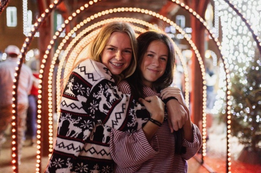 Girls hugging under Christmas lights