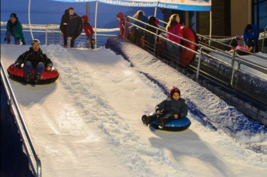 people riding a tube down fake snow