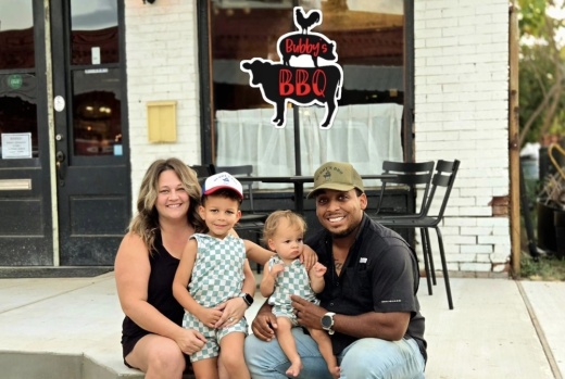 The owner, his wife, and their two children smile for a photo in front of the new spot.