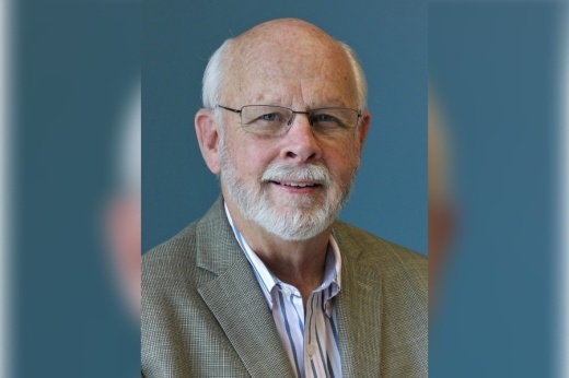 Male posing for a picture wearing brown sports coat and light colored button front shirt.