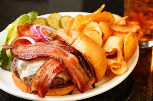 Hamburger with the top bun to the side showing a burger patty topped with cheese and bacon.
