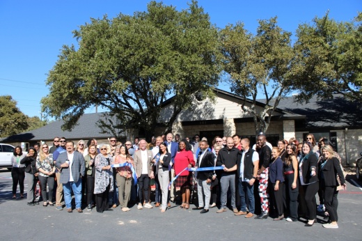 Officials with a wellness center pose outside for a ribbon-cutting picture.
