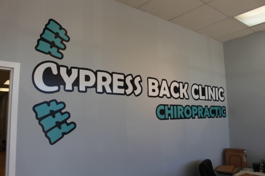 Cypress Back Clinic displays its branding on a wall behind its front desk for customers to see as they walk into the building.