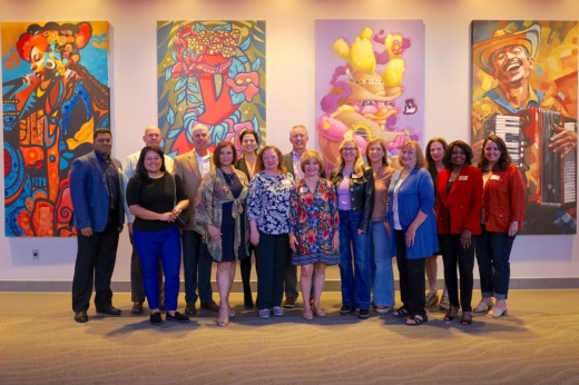 Sugar Land Cultural Arts Foundation board members gather in front of four murals chosen to be showcased inside the Smart Financial Center. (Courtesy Sugar Land Cultural Arts Foundation)