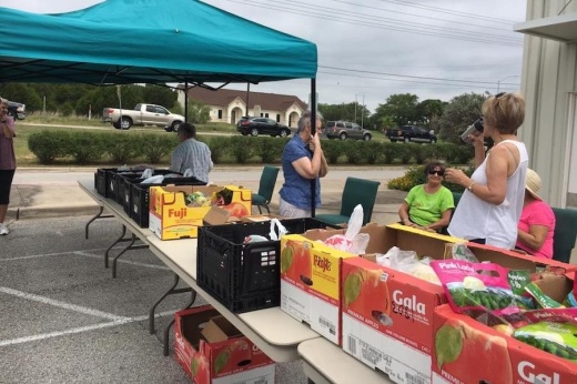 People distribute food outside at tables