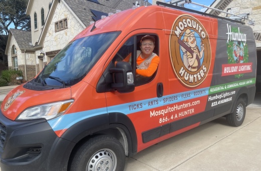 Mosquito Hunters employee poses inside of company car.