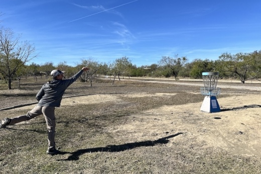 Tom Cowan throws a disc in a basket. (Thalia Guzman/Community Impact)