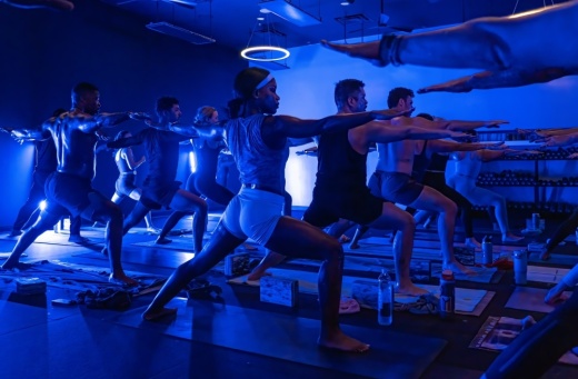 A group of people in a fitnes studio with a blue lighting filling the room.