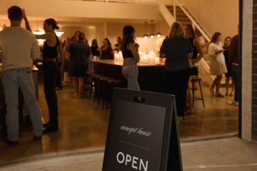 Open sign outside a large space with people gathered in groups.