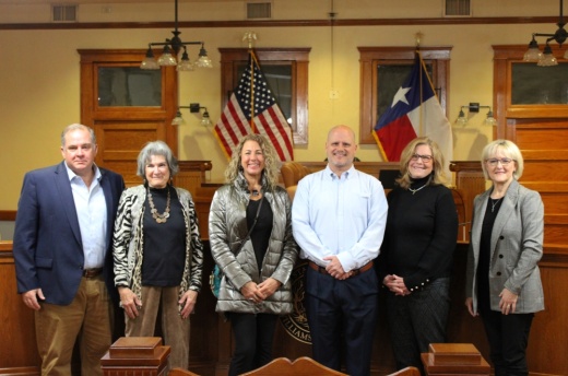 County and nonprofit leaders pose inside a courtroom.