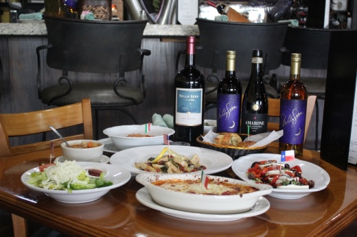 A table featuring Italian dishes and bottles of wine