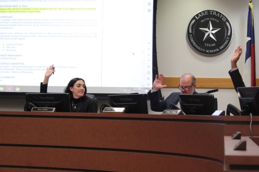 Two trustees raise their hands to take a vote