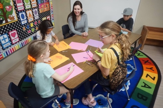 Group of elementary school aged children working on a craft around a table.