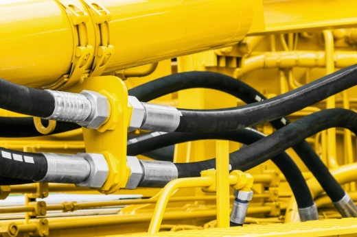 Hydraulic hoses are shown attached to a large yellow machine.