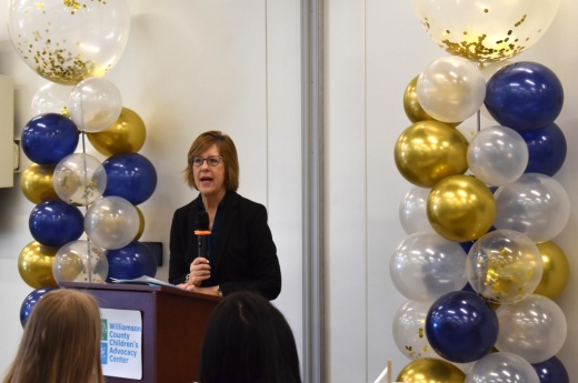 A judge stands at a podium inside a children's advocacy center.
