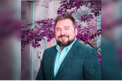 A man standing in front of purple leaves.