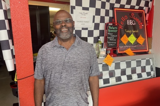 A man poses inside his BBQ shop.