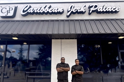 Caribbean Jerk Palace restaurant officials stand in front of the restaurant.