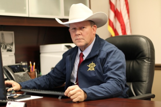 Sheriff poses at desk in county office.