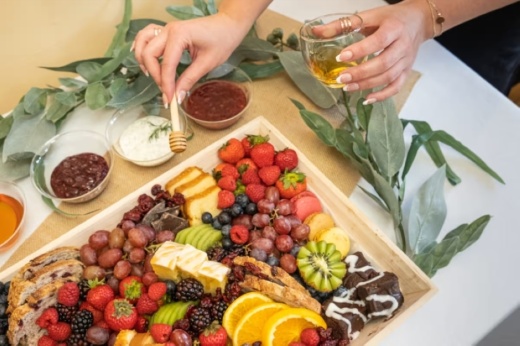 Charcuterie board overview with person's hands taking item from board.