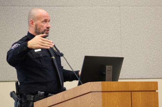 A police chief speaks at a podium to city council members.