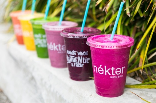 Various color juices and smoothies in cups with Nekter branding.