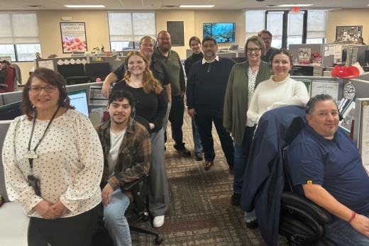 Team stands and sits in office.