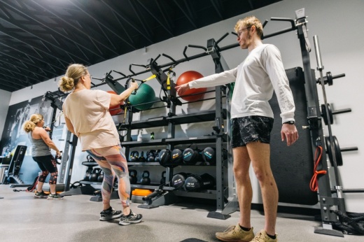 Personal trainer working with a client on gym equipment