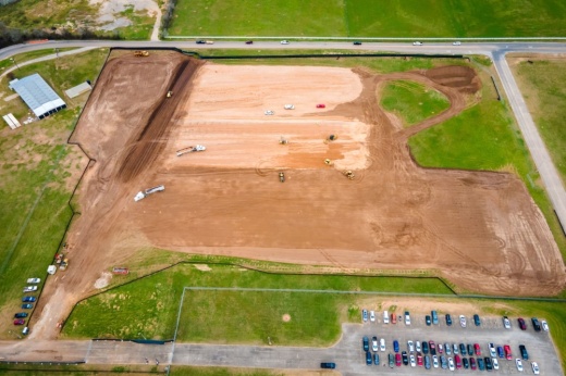 An aerial shot is shown with green grass and brown dirt.