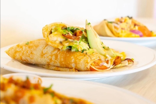 Crepe topped with avocado on a plate next to other plates of crepes.