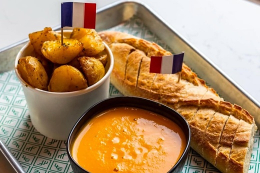 French soup, potatoes and baguette on a tray