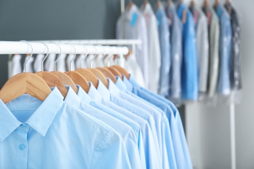 Clean shirts hang in a uniform manner on a rack.