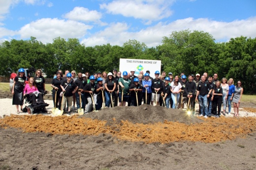 Group of males and females holding ceremonial shovels and hard hats at a groundbreaking event.