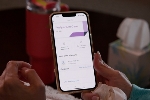 A woman holds a phone with the postpartum care app