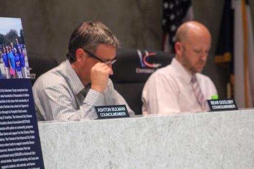 Two council members in Universal City, Texas sit at the dais next to the name tag of a departed council member who resigned during the meeting.