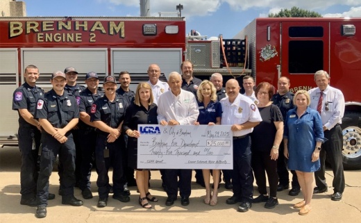 Firefighters and LCRA representatives posing with a check in front of a fire engine.
