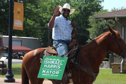 Ishmael Harris sits on his horse along Main Street in Bastrop and waves at the camera.