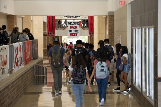 a group of high school students walk down a hallway