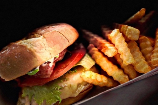 A chicken sandwich along with a stack of fries.