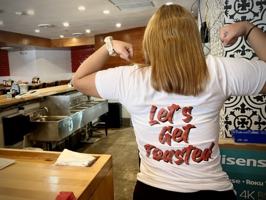 A staff member at Texas Toast poses in uniform at the new location on Guadalupe Street, now open near The University of Texas at Austin campus. (Haley McLeod/Community Impact)