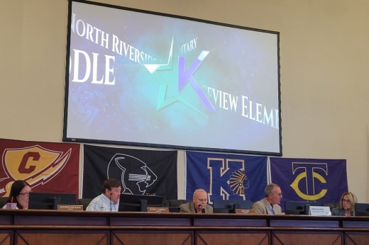 The dais at the Keller Education Center with a screen above the board members.