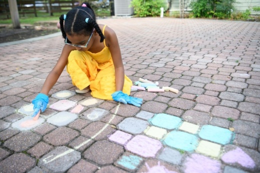 Charli Garza, who is on the autism spectrum, draws with chalk at Autism House in Magnolia. The business is one of several in the Tomball and Magnolia area that provide therapy and other services for people with autism. (Jamaal Ellis/Community Impact)