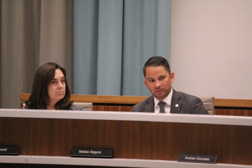 A woman and a man sit at a podium