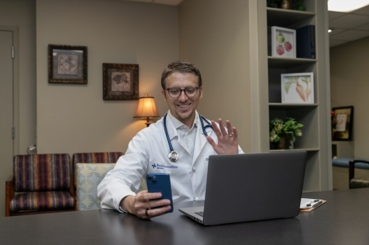 Doctor waving to patient through phone