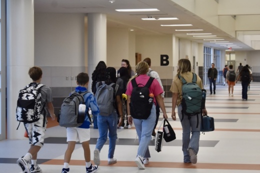 a group of middle school students walk down a hallway