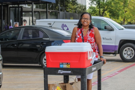 Volunteer pushing a cart of coolers and bagged food