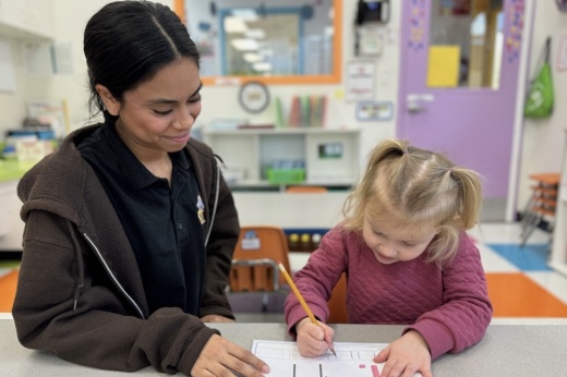 An image of an employee at the center helping a child.