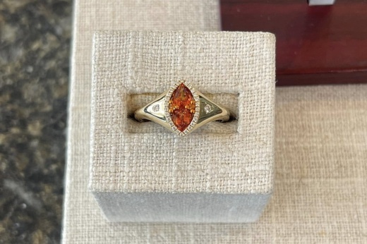 a red ring on a gold band with small diamonds on the sides